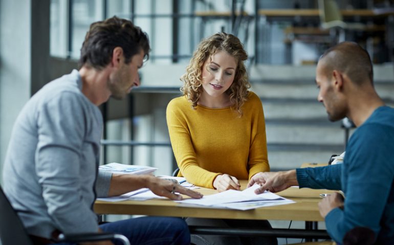 Coworkers working on project at table in modern studio