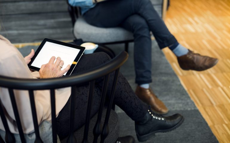 Low section of businesswoman using digital tablet during meeting at hotel lobby