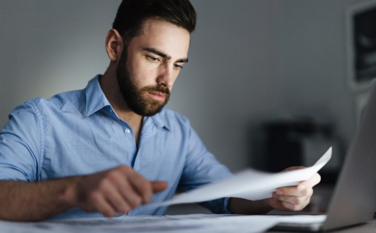 Businessman concentrating on learning sketch or data in document