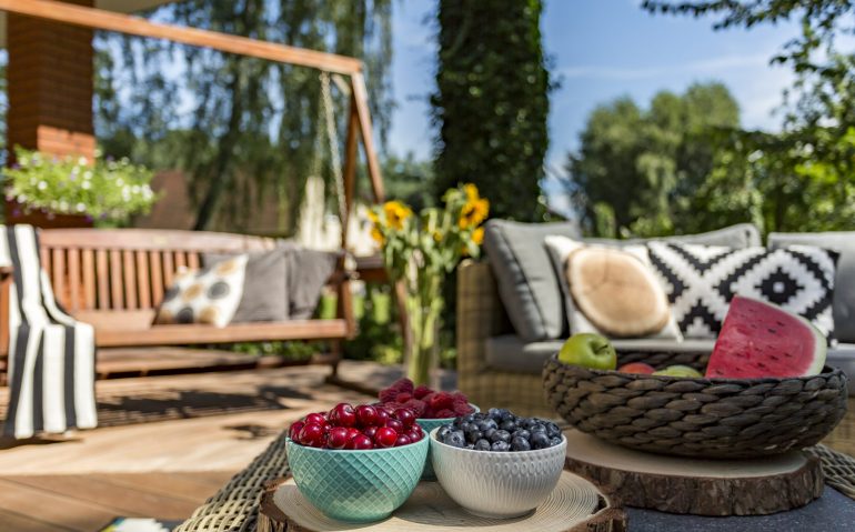 Summer feeling in the house garden with seasonal fruits and wooden furniture